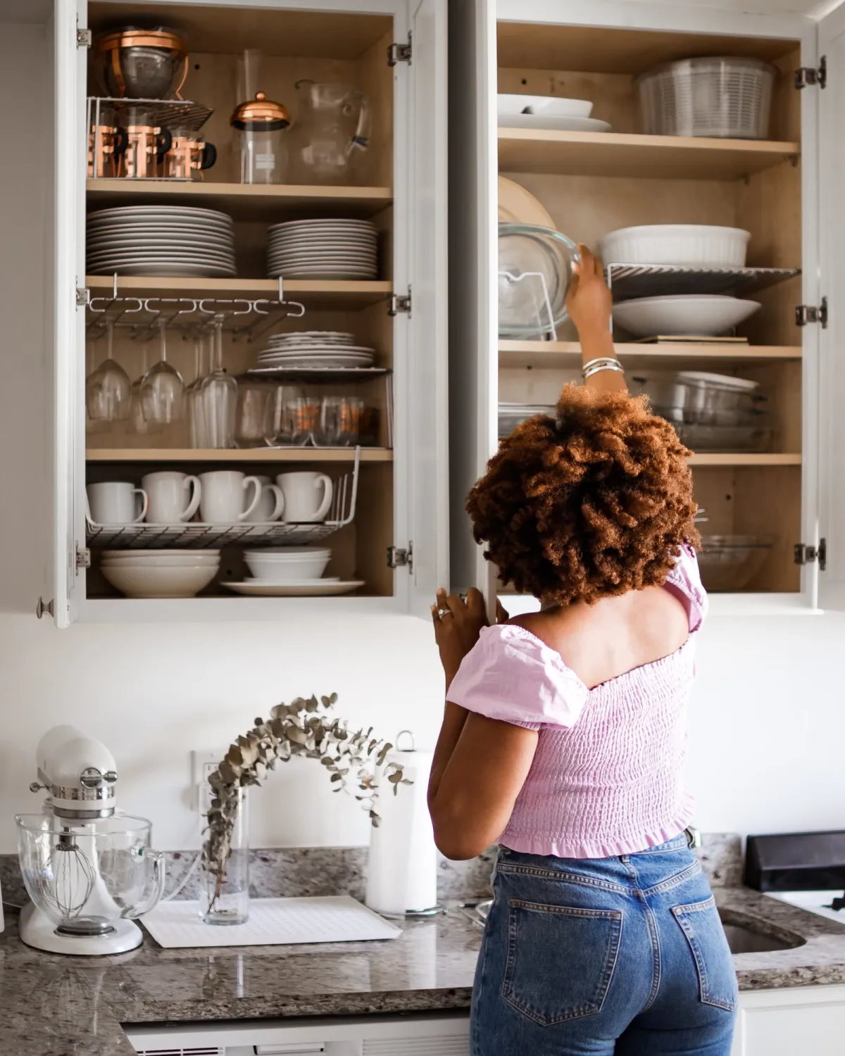 mulher mexendo em armário de cozinha