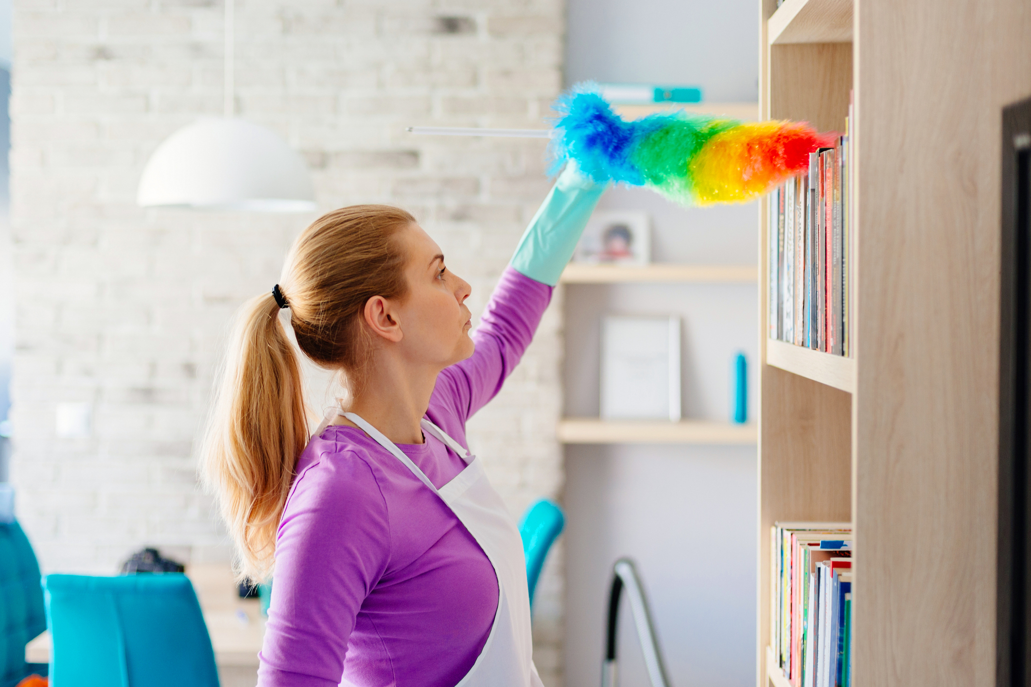 mulher limpando estante com livros