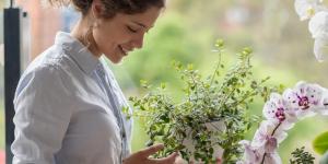 mulher sorrindo e segurando vaso com planta