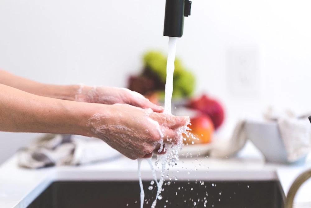 pessoa lavando as mãos na pia da cozinha