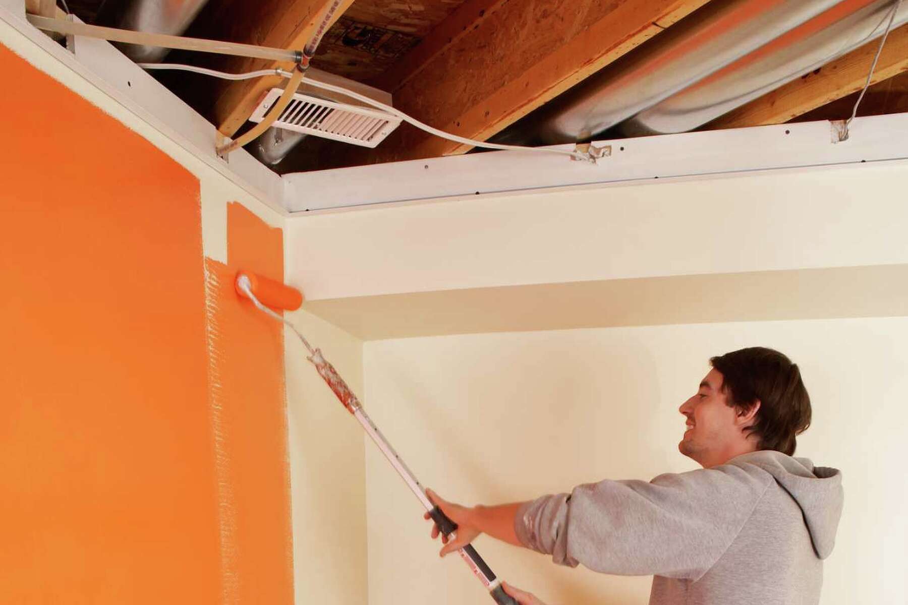 homem pintando parede de laranja