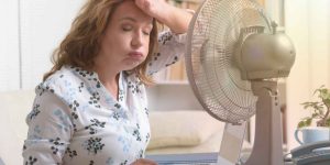 mulher com calor em frente a ventilador