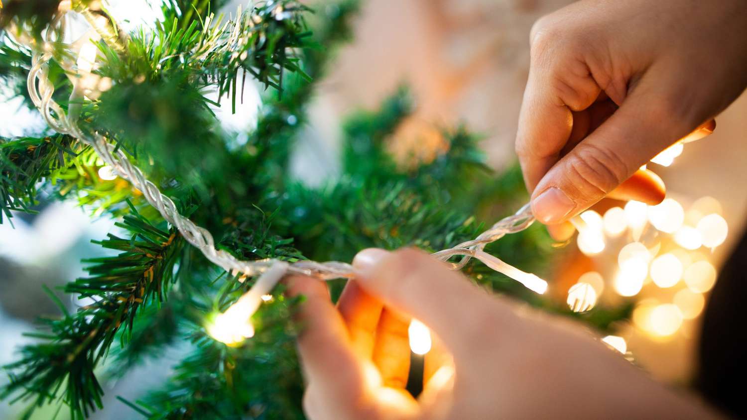 pessoa instalando pisca-piscas em árvore de Natal