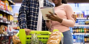 casal olhando lista de compras em supermercado