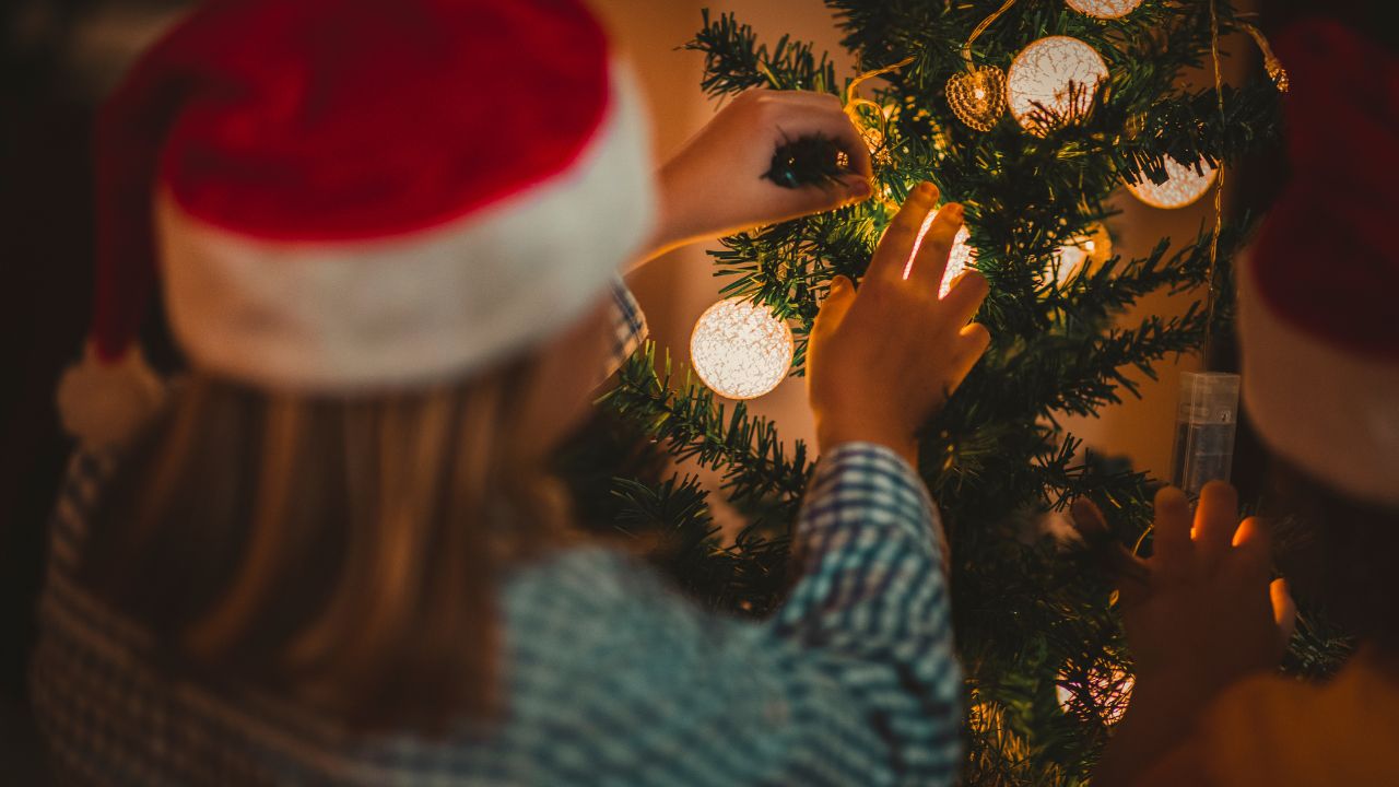 crianças colocando enfeites de natal na árvore