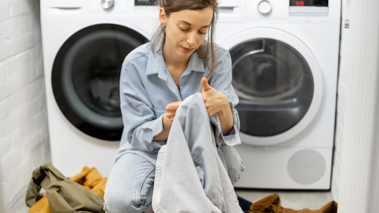 mulher separando roupas em frente à máquina de lavar